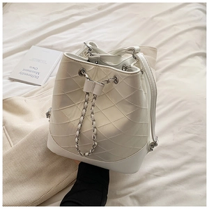 Detail of white quilted drawstring bucket bag with metal chain and solid base structure