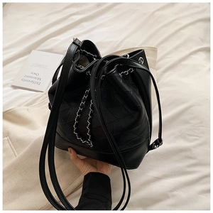 Detail view of black quilted bucket bag with metal chain drawstring and PU leather texture
