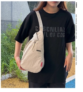 Détail d'un sac bandoulière en nylon beige avec plusieurs poches zippées et sangle réglable