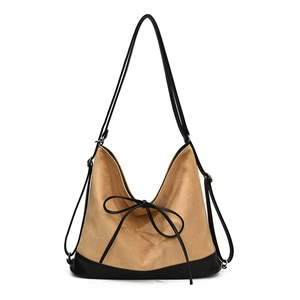Large beige suede and black leather tote bag with a decorative bow and versatile straps