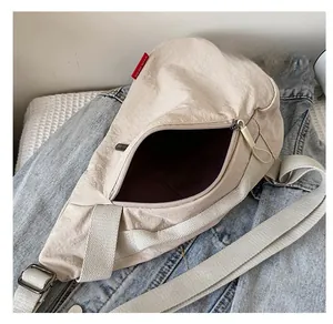 Détail de l'intérieur d'un sac bandoulière en nylon beige avec fermeture éclair et sangle