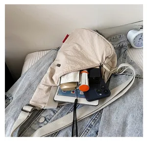 Détail de la capacité du sac bandoulière beige en nylon avec tablette et parapluie
