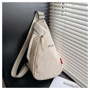 Détails de la texture plissée en nylon crème et de la fermeture éclair métallique du sac