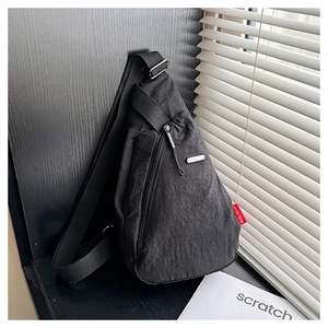 Détail du sac de poitrine en nylon noir avec étiquette tissée rouge et fermeture éclair