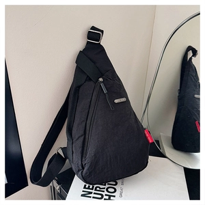 Vue détaillée du sac de poitrine en nylon noir avec logo argenté et étiquette de marque rouge