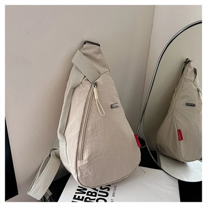 Détail du sac bandoulière beige en tissu texturé avec plaque logo métallique de marque
