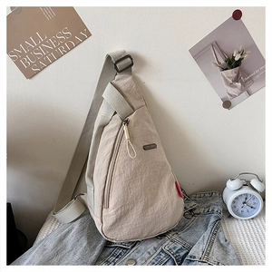 Détail du sac de poitrine en nylon beige clair avec texture froissée sur denim