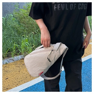 Détail du sac bandoulière en nylon beige avec sangle réglable et étiquette tissée rouge