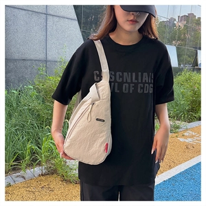 Détail du sac bandoulière en nylon beige clair avec texture plissée et double fermeture éclair