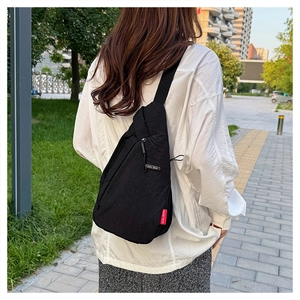 Détail du sac de poitrine EVOL GEAR en nylon noir avec étiquette rouge sur la rue