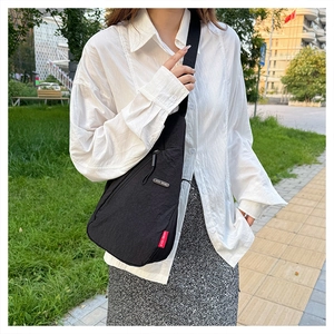 Gros plan extérieur d'un sac bandoulière en nylon noir avec plaque logo EVOL GEAR argentée