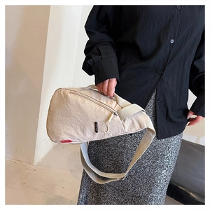 Détail du sac de poitrine blanc crème avec logo sur une tenue noire élégante