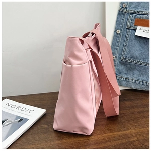 Detailed side view of pink nylon tote bag featuring a convenient side pocket on a wood desk