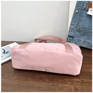 Detail of pink canvas tote bag with reinforced handles on a dark wood table