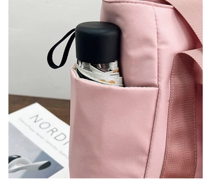 Detail view of pink canvas tote bag side pocket with a folding umbrella storage