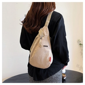 Vue détaillée du sac de poitrine en nylon beige avec plaque EVOL GEAR et étiquette rouge