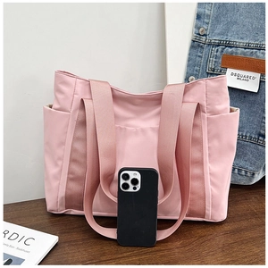 Pink canvas tote bag with side pockets showing size comparison with a smartphone