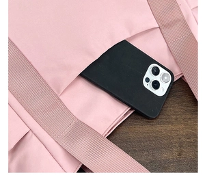 Macro detail of the pink nylon tote bag showing a side pocket with an iPhone inside