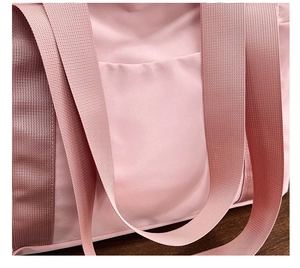 Detailed close-up of pink canvas tote bag with wide woven strap and side pocket
