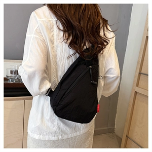 Détail du sac de poitrine en nylon noir avec étiquette tissée et fermeture éclair robuste