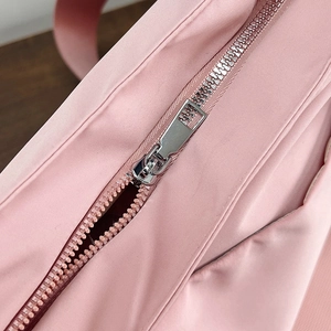 Detailed macro view of the silver metal zipper on a pale pink canvas tote bag