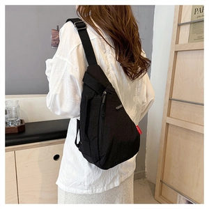 Détail du sac de poitrine en nylon noir imperméable montrant l'étiquette rouge latérale