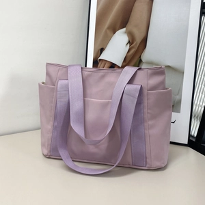 Detail of mauve nylon tote bag featuring wide web handles and functional side pockets