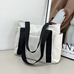 Minimalist cream canvas tote bag with black strap handles and practical front pocket