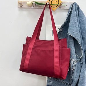 Detail of red nylon tote bag with functional exterior pockets and wide handles