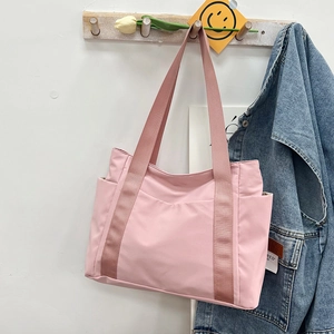 Pink canvas tote bag hanging on wooden hook showing side pockets and wide straps