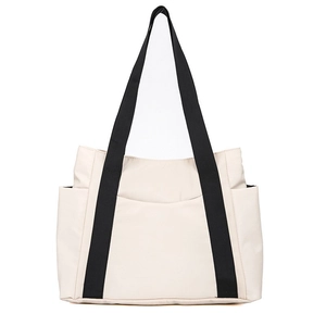 Detail view of large cream canvas tote bag with black straps and functional side pockets