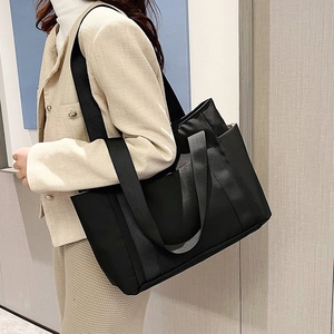 Side view of a large black nylon tote bag showing its capacity and wide woven straps