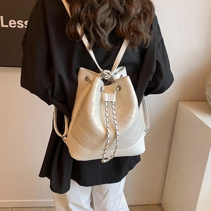 White quilted drawstring bucket backpack in shiny leather worn by a model from the back