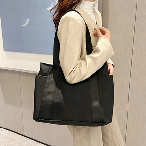 Close-up of black nylon tote bag showing side pocket detail and sleek fabric texture