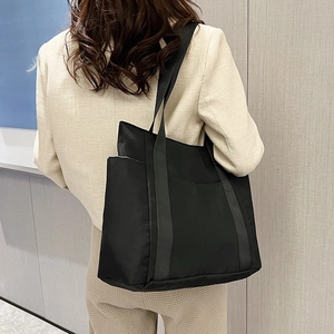 Detail of a black large capacity tote bag with reinforced handles and quality stitching