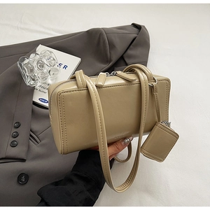 Detail of light beige rectangular handbag with twin handles and matching mini pouch accessory