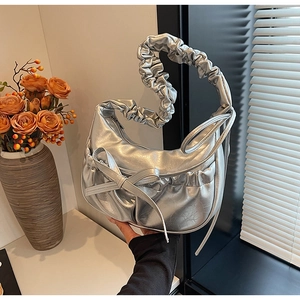 Detail of silver pleated crescent bag with bow decoration and textured faux leather