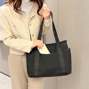 Detail of a black large-capacity tote bag with side pockets for daily commute and travel