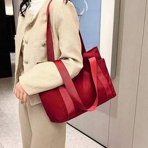 Side view of red nylon tote bag with wide strap and convenient side pocket detail