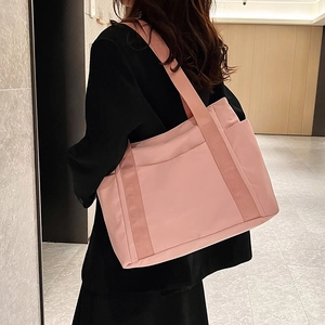 Pink minimalist tote bag featuring wide webbing handles and side pocket on a female model