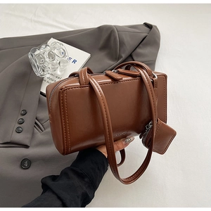 Detail of vintage brown rectangle handbag with mini pouch on a grey suit jacket