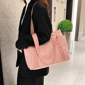 Detail of pink canvas tote bag with wide handles and adjustable strap on a model