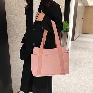 Close-up of pink nylon tote bag showing wide fabric straps and spacious side pockets
