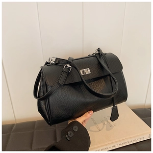 Detail of black lychee grain leather handbag with silver metal turn-lock and side charm