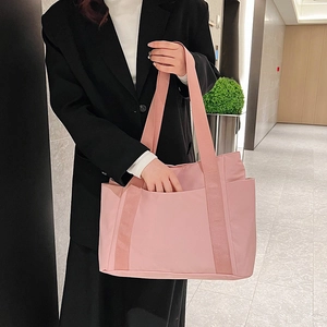 Close-up of a pink canvas tote bag showing wide shoulder straps and side pocket detail