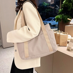 Detail of light beige canvas tote bag showing wide fabric strap and large side pocket