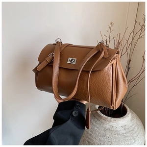 Detail of caramel brown faux leather underarm bag with lychee texture and silver twist lock