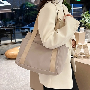 Detail of wide canvas shoulder strap and side pocket on a beige large tote bag