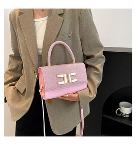 Kleine rosa Glitzertasche mit Goldverschluss an der Schulter der Frau getragen