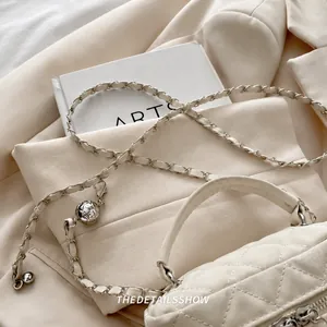 Detail of beige quilted mini bag with adjustable gold-ball chain shoulder strap